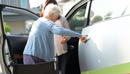 St John volunteer helping older person into a car