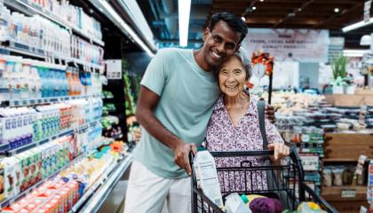 Young male volunteer at a supermarket helping an older woman