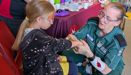 Young girl and St John volunteer making fake wounds
