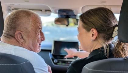 A photo of a community care volunteer driving an elderly passanger