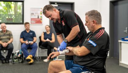 St John Trainer demonstrating bandaging someone in a first aid class