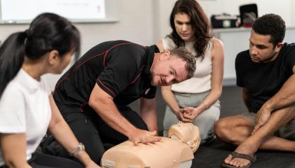 Photo of St John trainer demonstrating CPR to small group of students