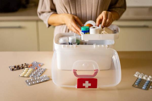 Person holding a first aid box with various medicines and first aid equipment