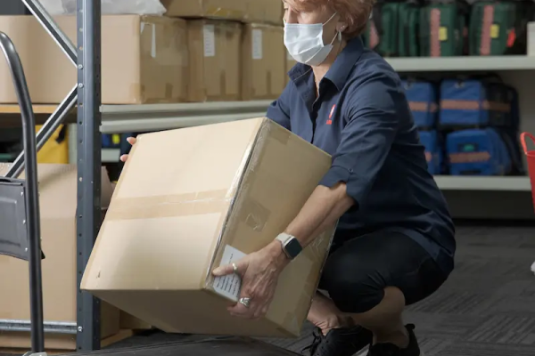 Woman squatting down with a straight back, to pick up a box 