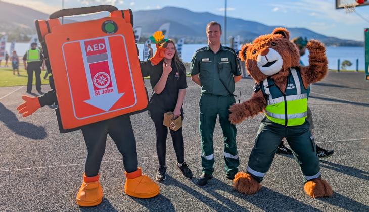 An St John G5 AED mascot posing with St John staff