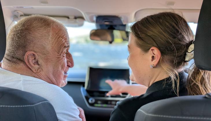 A photo of a community care volunteer driving an elderly passanger