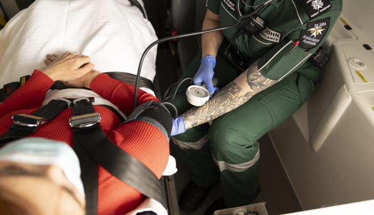 Women on stretcher in Ambulance having her blood pressure taken.