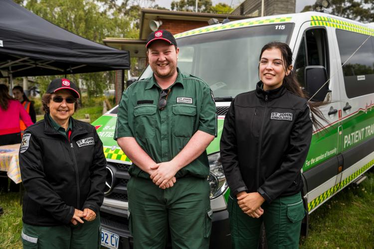 Three volunteers in front of ambulance