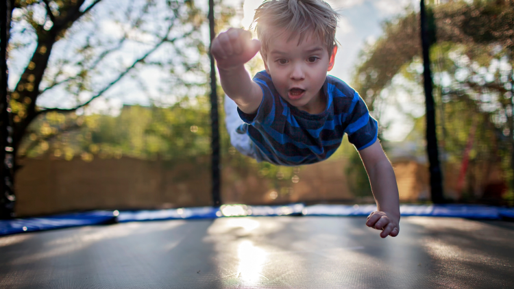 Young boy on trampoline in superman pose